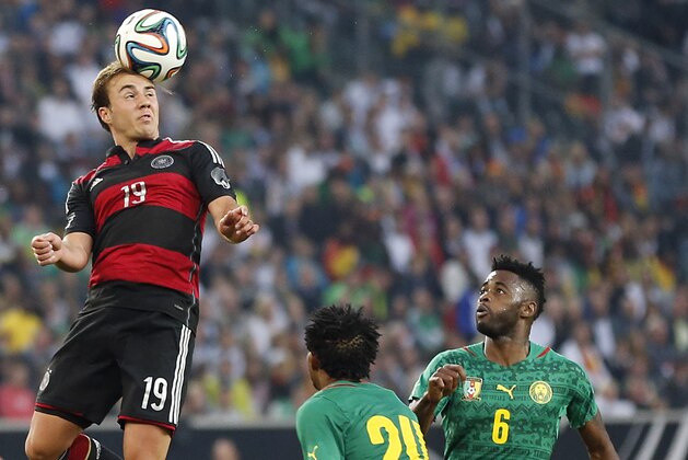 Germany's Mario Goetze, left, jumps  for the ball while Cameroon's Cedric Djeugoue, center, and Cameroon's Alexandre Song look on during a friendly WCup preparation soccer match between Germany and Cameroon in Moenchengladbach, Germany, Monday, June 2, 2014. (AP Photo/Frank Augstein)