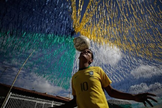 AP10ThingsToSee- Joao Paulo, 16, plays ball in a street decorated for the upcoming World Cup in the Ceilandia suburb of Brasilia, Brazil, Wednesday, June 4, 2014. The international soccer tournament is set to begin next week. (AP Photo/Eraldo Peres)