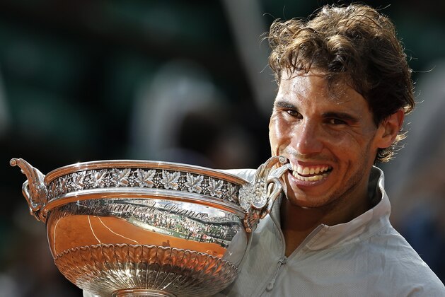 Spain's Rafael Nadal bites the trophy after winning the final of the French Open tennis tournament against Serbia's Novak Djokovic at the Roland Garros stadium, in Paris, France, Sunday, June 8, 2014. Nadal won in four sets 3-6, 7-5, 6-2, 6-4. (AP Photo/Darko Vojinovic)