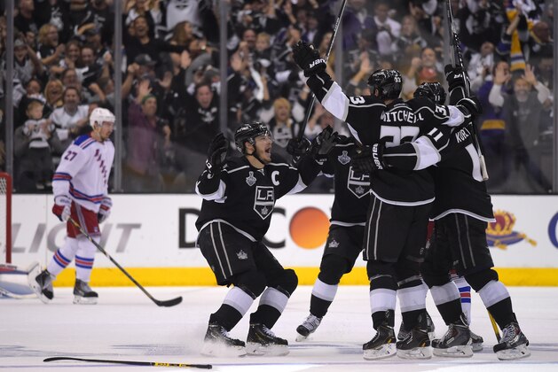 Los Angeles Kings' Dustin Brown, second from left, celebrates his game-winning goal with teammates as New York Rangers defenseman Ryan McDonagh, left, looks on in the second overtime period in Game 2 of the NHL hockey Stanley Cup Finals, Saturday, June 7, 2014, in Los Angeles. The Kings won 5-4.  (AP Photo/Mark J. Terrill)