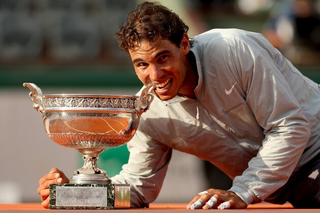 PARIS, FRANCE - JUNE 08:  Rafael Nadal of Spain bites the Coupe de Mousquetaires after victory in his men's singles final match against Novak Djokovic of Serbia on day fifteen of the French Open at Roland Garros on June 8, 2014 in Paris, France.  (Photo by Matthew Stockman/Getty Images)