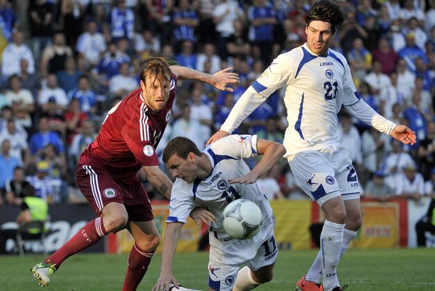 Latvia's Kaspars Gorkss, left,  vies for the ball with Bosnia's Edin Dzeko, centre, and Ervin Zukanovic during their World Cup 2014 Group G qualification match, in Riga, Latvia,  Friday, June 7, 2013. (AP Photo/Roman Koksarov)