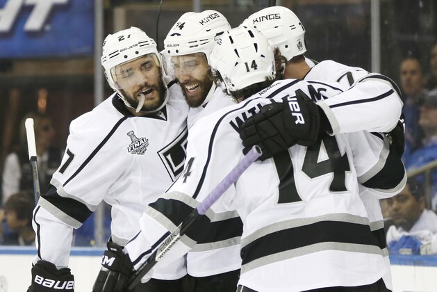 Los Angeles Kings, from left, Alec Martinez (27), Dwight King (74), Jeff Carter, and Justin Williams (14) celebrate after a goal by Carter against the New York Rangers to end the first period during Game 3 of the NHL hockey Stanley Cup Final, Monday, June 9, 2014, in New York. (AP Photo/Kathy Willens)
