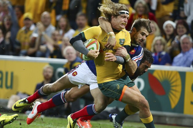 Australian left wing Nick Cummins, left, is tackled by French fullback Hugo Bonneval during their Rugby test match in Brisbane, Australia, Saturday, June 7, 2014. (AP Photo/Tertius Pickard)