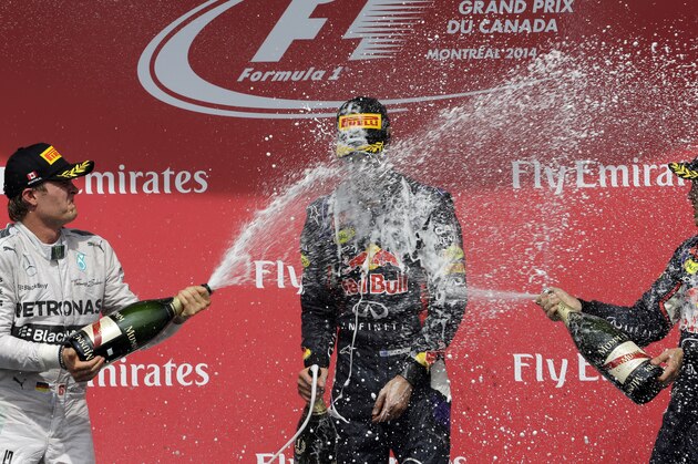 Red Bull driver Daniel Ricciardo, center, from Australia, is sprayed with Champagne by Mercedes driver Nico Rosberg, left, from Germany, and fellow Red Bull driver Sebastian Vettel, right, from Germany, after winning  the Canadian Grand Prix auto race, Sunday, June 8, 2014, in Montreal. Rosberg finished second and Vettel was third. (AP Photo/David J. Phillip)