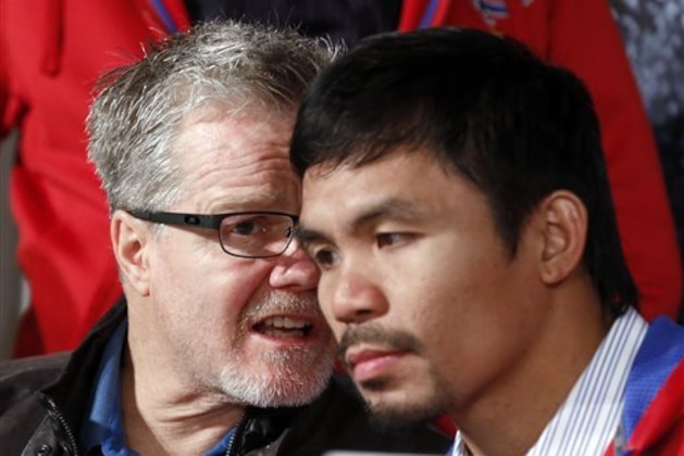 CORRECTS PACQUIAO TO RIGHT, NOT LEFT - Manny Pacquiao, right of the Philippines, right, listens to his trainer Freddie Roach, during a boxing news conference, Tuesday, Feb. 4, 2014, in Beverly Hills, Calif., to promote their upcoming WBO welterweight championship boxing rematch against Tim Bradley. Pacquiao and Bradley's first match on June 9, 2012 was a split decision in favor of Bradley, which ended Pacquiao's welterweight title reign as well as his seven-year, 15-bout winning streak.  Pacquiao vs. Bradley 2 will take place Saturday, April 12, 2014, in Las Vegas. (AP Photo/Reed Saxon)