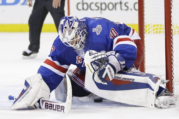 A shot on goal by the Los Angeles Kings slips through the legs of New York Rangers goalie Henrik Lundqvist (30) to rest near the goal line before being swatted out by Rangers center Derek Stepan in the third period during Game 4 of the NHL hockey Stanley Cup Final, Wednesday, June 11, 2014, in New York. The Rangers won 2-1. (AP Photo/Seth Wenig)