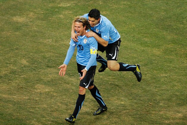 JOHANNESBURG, SOUTH AFRICA - JULY 02: Luis Suarez celebrates with Diego Forlan of Uruguay celebrates after he scored his team's first goal from a free kick during the 2010 FIFA World Cup South Africa Quarter Final match between Uruguay and Ghana at the Soccer City stadium on July 2, 2010 in Johannesburg, South Africa.  (Photo by Dominic Barnardt/Getty Images)