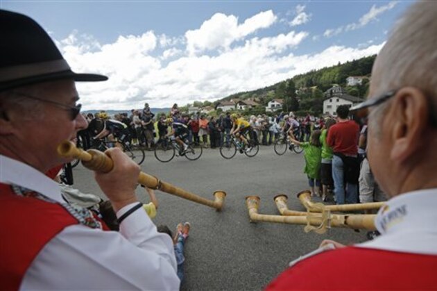Traditional Swiss horn blowers are seen in the foreground as the pack with Bradley Wiggins of Britain, wearing the overall leader's yellow jersey, passes during the 8th stage of the Tour de France cycling race over 157.5 kilometers (98.5 miles) with start in Belfort, France, and finish in Porrentruy, Switzerland, Sunday July 8, 2012. (AP Photo/Laurent Cipriani)