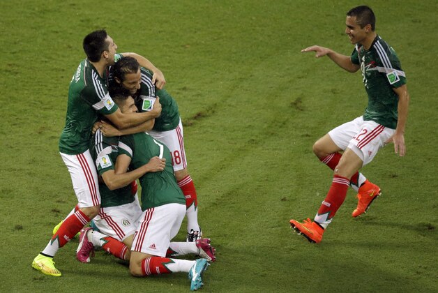 Mexico's players celebrate after Mexico's Oribe Peralta scored during the group A World Cup soccer match between Mexico and Cameroon in the Arena das Dunas in Natal, Brazil, Friday, June 13, 2014.  (AP Photo/Hassan Ammar)