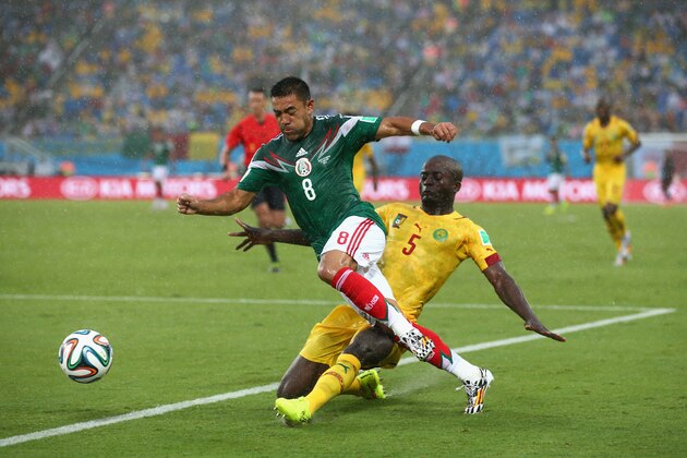 NATAL, BRAZIL - JUNE 13: Marco Fabian of Mexico is tackled by Dany Nounkeu of Cameroon during the 2014 FIFA World Cup Brazil Group A match between Mexico and Cameroon at Estadio das Dunas on June 13, 2014 in Natal, Brazil.  (Photo by Julian Finney/Getty Images)