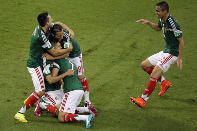 Mexico's players celebrate after Mexico's Oribe Peralta scored during the group A World Cup soccer match between Mexico and Cameroon in the Arena das Dunas in Natal, Brazil, Friday, June 13, 2014.  (AP Photo/Hassan Ammar)