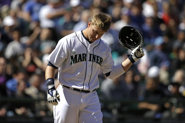 Seattle Mariners' Justin Smoak pulls his helmet off after striking out against the Oakland Athletics in a baseball game Sunday, April 13, 2014, in Seattle. (AP Photo/Elaine Thompson)