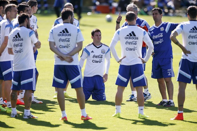 Argentina's Lionel Messi, center, kneels after putting on his shoes as the team gathers at centerfield at the start of a training session in Vespasiano, near Belo Horizonte, Brazil, Friday, June, 13, 2014. Argentina will play in group F of the Brazil 2014 soccer World Cup. (AP Photo/Victor R. Caivano)