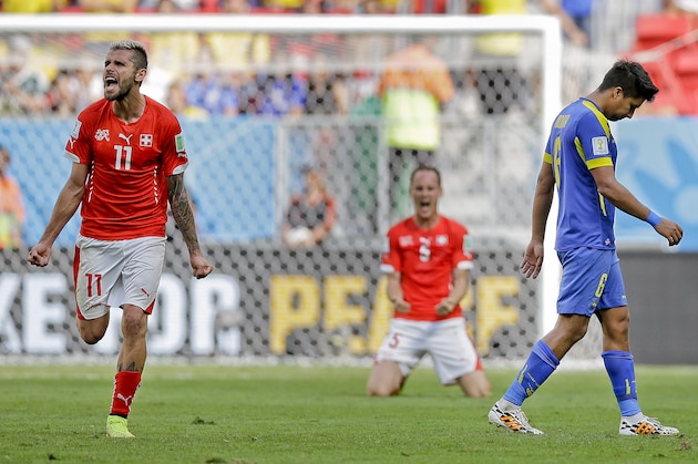 Ecuador's Cristhian Noboa, right, leaves the pitch as Switzerland's Valon Behrami, left, and Stephan Lichtsteiner celebrate after the group E World Cup soccer match between Switzerland and Ecuador at the Estadio Nacional in Brasilia, Brazil, Sunday, June 15, 2014. Switzerland won the match 2-1. (AP Photo/Michael Sohn)