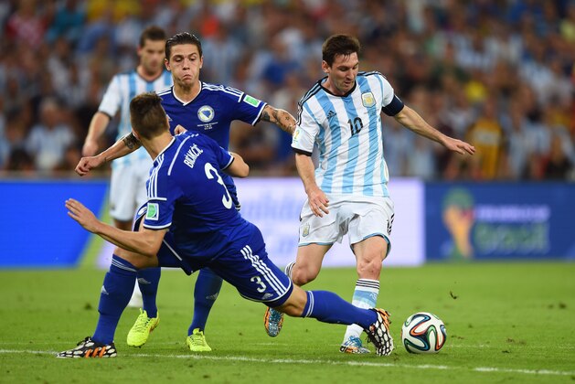 RIO DE JANEIRO, BRAZIL - JUNE 15:  Lionel Messi of Argentina controls the ball on his way to scoring his team's second goal against Ermin Bicakcic (L) and Muhamed Besic of Bosnia and Herzegovina during the 2014 FIFA World Cup Brazil Group F match between Argentina and Bosnia-Herzegovina at Maracana on June 15, 2014 in Rio de Janeiro, Brazil.  (Photo by Matthias Hangst/Getty Images)