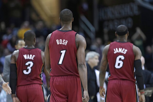 Miami Heat's Dwyane Wade (3), Chris Bosh and LeBron James walk back to the bench after a timeout during an NBA basketball game against the Cleveland Cavaliers Wednesday, March 20, 2013, in Cleveland. (AP Photo/Tony Dejak)