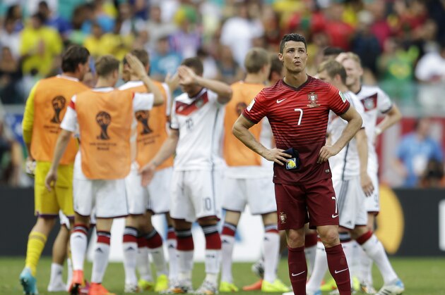Portugal's Cristiano Ronaldo stands on the pitch as German players celebrate following Portugal's 4-0 loss to Germany during the group G World Cup soccer match between Germany and Portugal at the Arena Fonte Nova in Salvador, Brazil, Monday, June 16, 2014.  (AP Photo/Natacha Pisarenko)