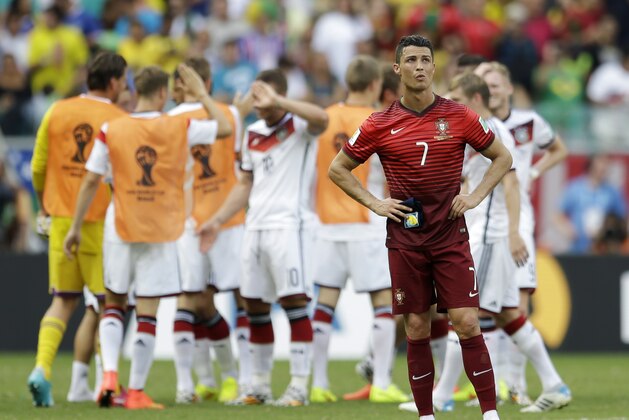 Portugal's Cristiano Ronaldo stands on the pitch as German players celebrate following Portugal's 4-0 loss to Germany during the group G World Cup soccer match between Germany and Portugal at the Arena Fonte Nova in Salvador, Brazil, Monday, June 16, 2014.  (AP Photo/Natacha Pisarenko)