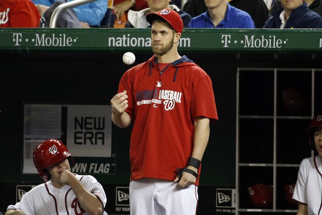 Washington Nationals left fielder Bryce Harper, center, tosses a ball as he stands in the dugout during a baseball game against the New York Mets at Nationals Park Friday, May 16, 2014, in Washington. (AP Photo/Alex Brandon)