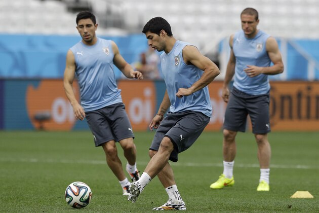 Uruguay national soccer team player Luis Suarez, center, passes a ball as he takes part in a squad training session for the 2014 soccer World Cup at Itaquerao Stadium in Sao Paulo, Brazil, Wednesday, June 18, 2014.  Uruguay play England in group D of the 2014 soccer World Cup at the stadium on Thursday.  (AP Photo/Matt Dunham)
