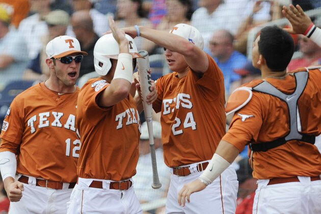 Texas players including Parker French (24) and Jacob Felts (12) greet Collin Shaw, center, to the dugout after he scored against UC Irvine in the second inning of an NCAA baseball College World Series game on a bunt by teammate Zane Gurwitz, in Omaha, Neb., Saturday, June 14, 2014. . (AP Photo/Dave Weaver)