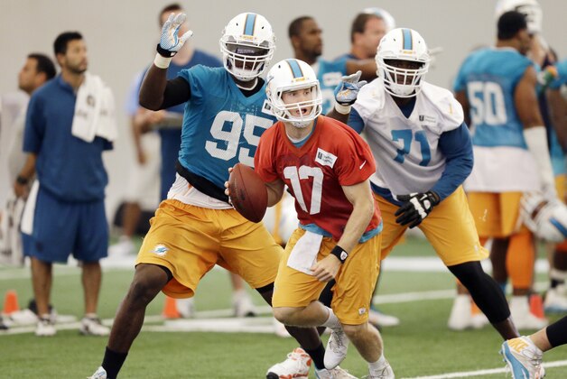 Miami Dolphins quarterback Ryan Tannehill, foreground, looks for an open teammate during mini-camp, Tuesday, June 17, 2014 at the Dolphins Training Facility in Davie, Fla. defensive end Dion Jordan (95) and tackle Branden Albert (71) are at rear. (AP Photo/Wilfredo Lee)