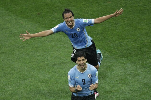 Uruguay's Luis Suarez, front, is chased by his teammate Alvaro Gonzalez as he celebrates scoring the opening goal during the group D World Cup soccer match between Uruguay and England at the Itaquerao Stadium in Sao Paulo, Brazil, Thursday, June 19, 2014.  (AP Photo/Michael Sohn)