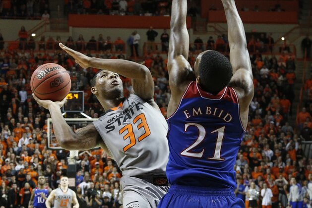 Oklahoma State guard Marcus Smart (33) shoots in front of Kansas center Joel Embiid (21) in the second half of an NCAA college basketball game in Stillwater, Okla., Saturday, March 1, 2014. Oklahoma State won 72-65. (AP Photo/Sue Ogrocki)