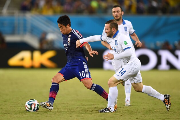 NATAL, BRAZIL - JUNE 19: Shinji Kagawa of Japan controls the ball against Dimitris Salpingidis of Greece during the 2014 FIFA World Cup Brazil Group  C match between Japan and Greece at Estadio das Dunas on June 19, 2014 in Natal, Brazil.  (Photo by Jamie McDonald/Getty Images)