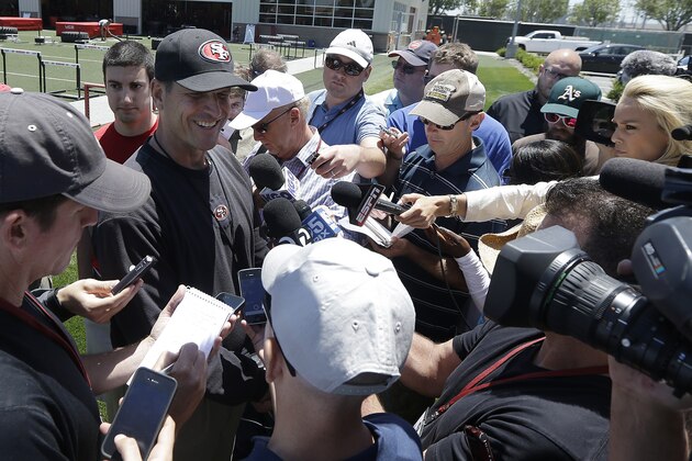San Francisco 49ers head coach Jim Harbaugh, left, smiles while speaking to reporters during NFL football minicamp in Santa Clara, Calif., Thursday, June 19, 2014. (AP Photo/Jeff Chiu)