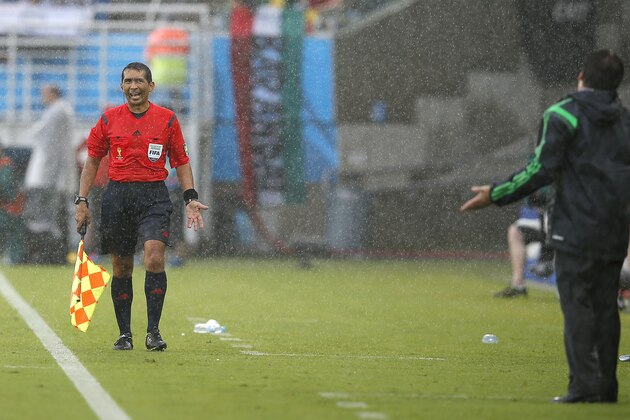 FILE - the June 13, 2014 file photo shows assistant referee Humberto Clavijo from Colombia argue ingwith Mexico's head coach Miguel Herrera, right, during the first half of the group A World Cup soccer match between Mexico and Cameroon in the Arena das Dunas in Natal, Brazil. FIFA has replaced the Colombian assistant referee whose offside decisions denied Mexico two potential goals against Cameroon. FIFA said Humberto Clavijo will not be in referee Wilmar Roldan's team for South Korea vs. Algeria in Porto Alegre on Sunday.  (AP Photo/Eduardo Verdugo, file)