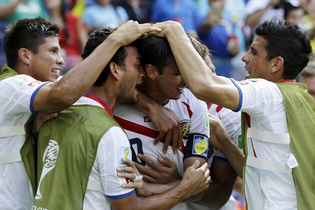 Costa Rica's Bryan Ruiz, center, is congratulated by teammates after scoring his side's first goal over Italy's goalkeeper Gianluigi Buffon during the group D World Cup soccer match between Italy and Costa Rica at the Arena Pernambuco in Recife, Brazil, Friday, June 20, 2014.  (AP Photo/Ricardo Mazalan)