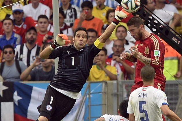 Chile's goalkeeper Claudio Bravo, left, clears the ball from Spain's Sergio Ramos during the group B World Cup soccer match between Spain and Chile at the Maracana Stadium in Rio de Janeiro, Brazil, Wednesday, June 18, 2014.  (AP Photo/Manu Fernandez)