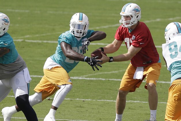 Miami Dolphins quarterback Ryan Tannehill, right, hands off to running back Lamar Miller during a scrimmage on the final day of NFL football minicamp, Thursday, June 19, 2014, at the team's training Facility in Davie, Fla. (AP Photo/Wilfredo Lee)