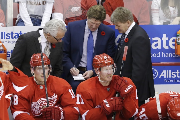 Tom Renney, associate coach, left, head coach Mike Babcock, center, and assistant coach Bill Peters talk during the overtime period of an NHL hockey game in Detroit, Saturday, Nov. 9, 2013. (AP Photo/Carlos Osorio)