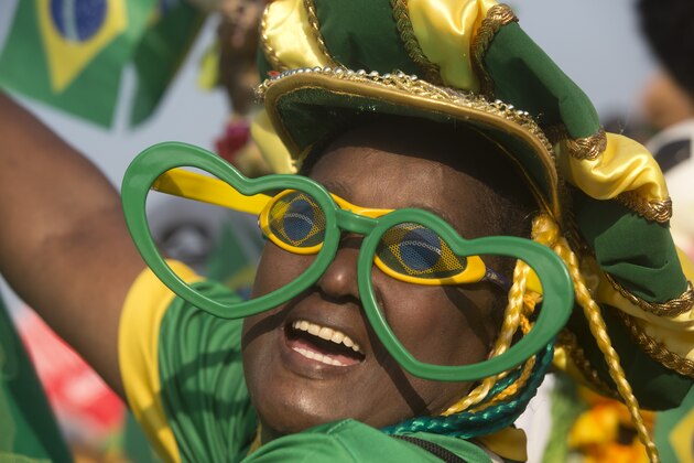 A Brazil soccer fan in costume cheers before the start of a live broadcast of a World Cup match between Brazil and Mexico inside the FIFA Fan Fest area on Copacabana beach, in Rio de Janeiro, Brazil, Tuesday, June 17, 2014. (AP Photo/Silvia Izquierdo)