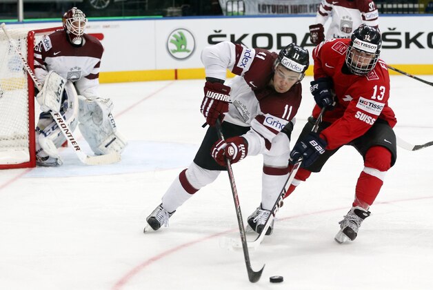 Switzerland forward Kevin Fiala, right, battles for the puck with Latvia defender Kristaps Sotnieks during the Group B preliminary round match between Switzerland and Latvia at the Ice Hockey World Championship in Minsk, Belarus, Tuesday, May 20, 2014. (AP Photo/Darko Bandic)