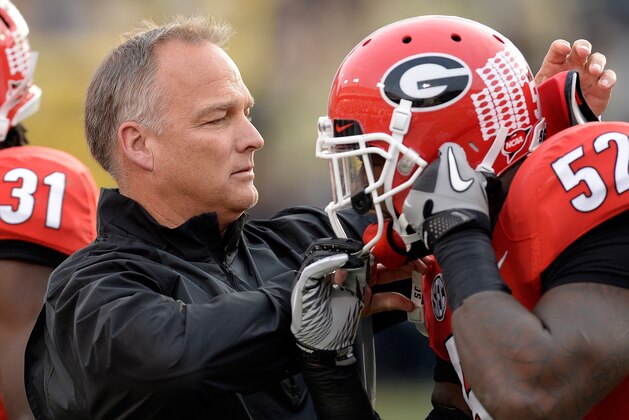 Georgia head coach Mark Richt, left, adjusts a hemet for defensive lineman De'Andre Johnson (57) during the first half of an NCAA football game on Saturday, Nov. 30, 2013, in Atlanta. (AP Photo/David Tulis)
