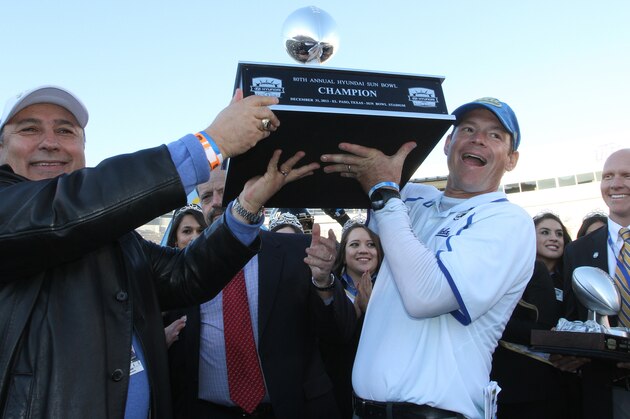 UCLA head football coach Jim Mora, right, and athletic director Dan Guerrero held up the Sun Bowl championship trophy after defeating Virginia Tech 42-12 in an NCAA college football game Tuesday Dec. 31, 2013, in El Paso, Texas. (AP Photo/Victor Calzada)