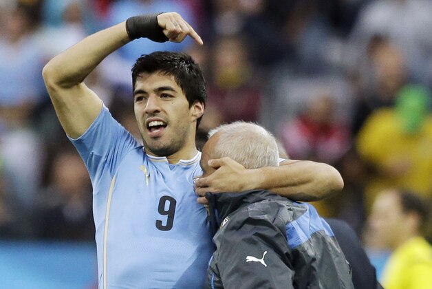 RESENDING TO ADD NAME OF PHYSIOTHERAPIST - Uruguay's Luis Suarez, left, celebrates with the physiotherapist Walter Ferreira after scoring the opening goal during the group D World Cup soccer match between Uruguay and England at the Itaquerao Stadium in Sao Paulo, Brazil, Thursday, June 19, 2014.   (AP Photo/Matt Dunham)