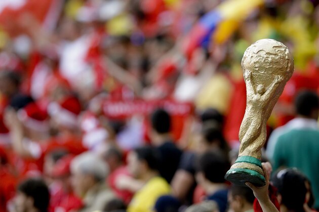 A spectator holds up a replica of the World Cup trophy after the group E World Cup soccer match between Switzerland and Ecuador at the Estadio Nacional in Brasilia, Brazil, Sunday, June 15, 2014. (AP Photo/Michael Sohn)