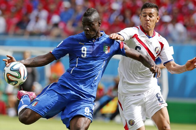 Italy's Mario Balotelli, left, gets in a shot despite the challenge of Costa Rica's Oscar Duarte during the group D World Cup soccer match between Italy and Costa Rica at the Arena Pernambuco in Recife, Brazil, Friday, June 20, 2014.  (AP Photo/Frank Augstein)