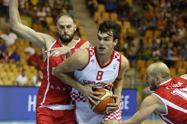 Croatia's Dario Saric, center, drives a ball past Georgia's Besik Lezhava, right, and Georgia's Viktor Sanikidze, left, during their EuroBasket European Basketball Championship Group C match in Celje, Slovenia, Thursday, Sept. 5, 2013. (AP Photo/Petr David Josek)