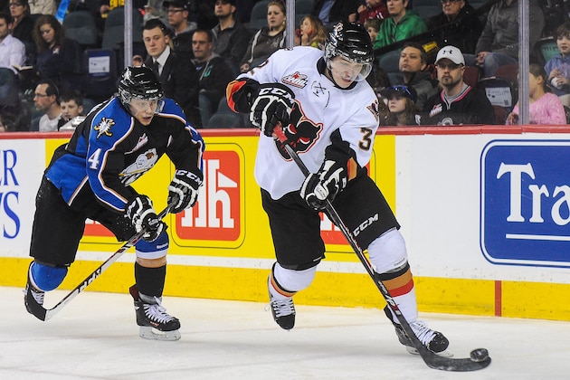CALGARY, AB - MARCH 15: Travis Sanheim #32 of the Calgary Hitmen skates with the puck past Jaedon Descheneau #14 of the Kootenay Ice during a WHL game at Scotiabank Saddledome on March 15, 2014 in Calgary, Alberta, Canada. (Photo by Derek Leung/Getty Images)