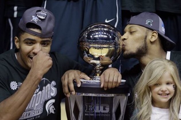 FILE - In this March 16, 2014 file photo, Michigan State's Gary Harris, left, poses with the championship trophy as Adreian Payne kisses it after they  defeated Michigan 69-55 in an NCAA college basketball game in the championship of the Big Ten Conference tournament in Indianapolis. Lacey Holsworth, who is batling cancer,  smiles at right foreground. The father of  8-year-old Lacey Holsworth, who befriended Michigan State basketball star Adreian Payne says his daughter has died. Matt Holsworth says Lacey Holsworth died at their St. Johns, Mich., home late Tuesday, April 8, 2014,