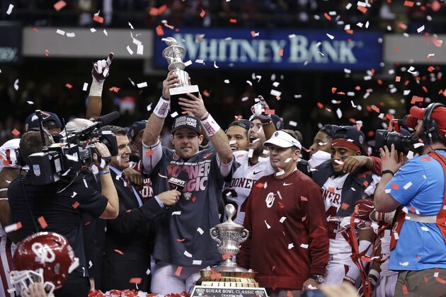 Oklahoma quarterback Trevor Knight holds the MVP trophy as he stands with Oklahoma head coach Bob Stoops and the Sugar Bowl trophy after the NCAA college football matchup in New Orleans, Thursday, Jan. 2, 2014.  Oklahoma won 45-31. (AP Photo/Rusty Costanza)