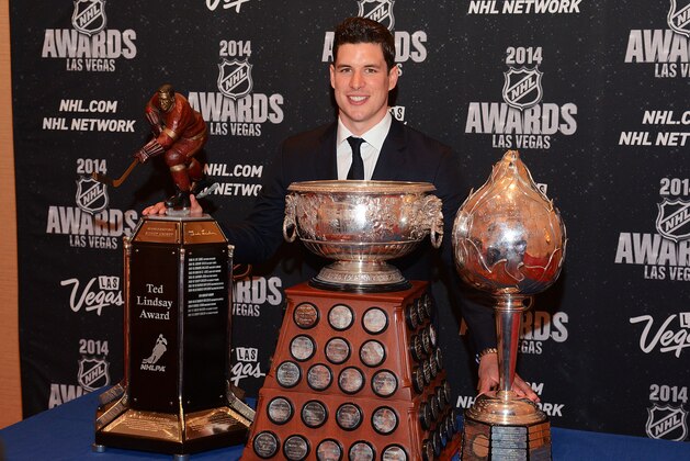 In this photo provided by the Las Vegas News Bureau, Sidney Crosby of the Pittsburgh Penguins poses with the Ted Lindsay Award for being voted most outstanding player in the league by the players, the Art Ross Trophy for leading the league in scoring points, and the Hart Memorial Trophy which recognizes the most valuable player to his team, at the 2014 NHL Awards at Wynn Las Vegas. Tuesday, June 24, 2014. (AP Photo/Las Vegas News Bureau, Steve Spatafore)