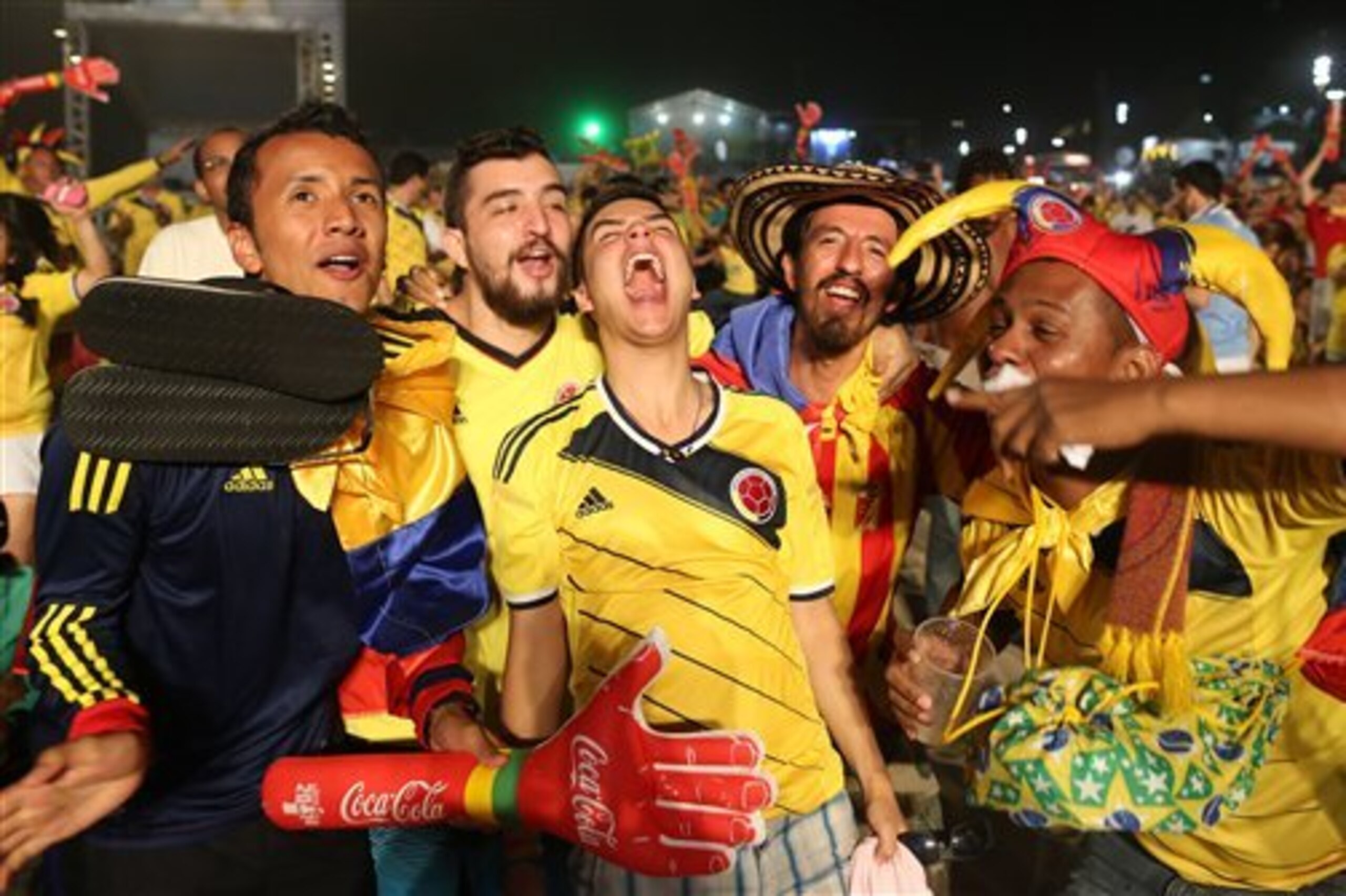 Colombia soccer fans celebrate the second goal scored by their team as they watch a live telecast of their team's World Cup against with Japan inside the FIFA Fan Fest area on Copacabana beach, in Rio de Janeiro, Brazil, Tuesday, June 24, 2014. Substitute James Rodriguez scored a brilliant goal and set up two more for Jackson Martinez as Colombia beat Japan 4-1 on Tuesday to confirm top spot in Group C and eliminate the Asian champions from the World Cup.  (AP Photo/Leo Correa)