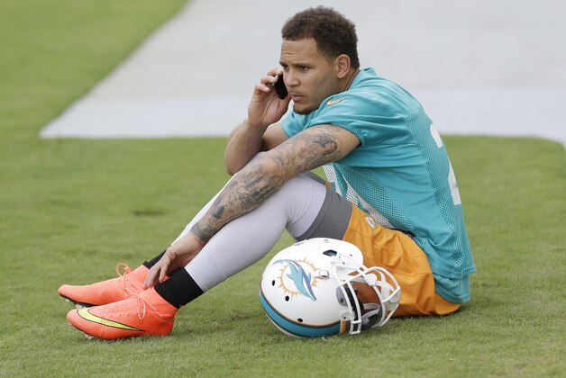 Miami Dolphins cornerback Cortland Finnegan talks on a cell phone after NFL football mini camp, Wednesday, June 18, 2014, in Davie, Fla. He sat out team drills for the second straight day, giving Jamar Taylor a chance to match up with starting receivers Mike Wallace and Brian Hartline. (AP Photo/Wilfredo Lee)
